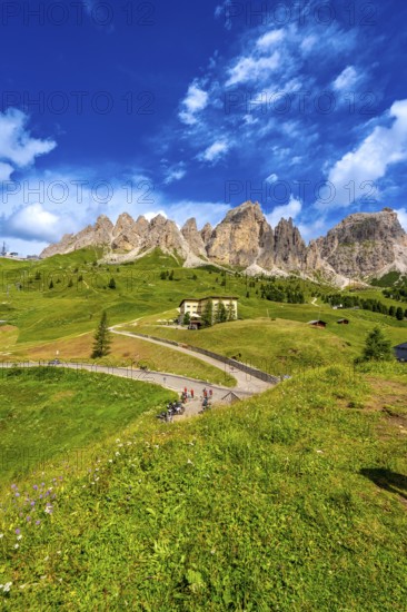 Bikers taking a break at gardena pass admiring the stunning view of the dolomites on a sunny summer