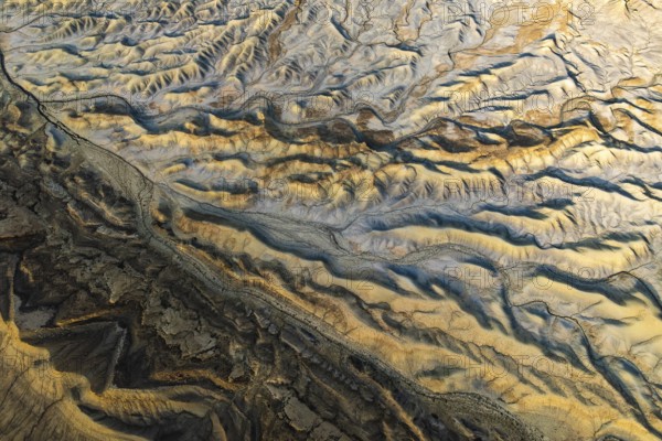 Aerial view showcasing the unique textures of a golden sandstone desert in Utah, USA. The sunlight