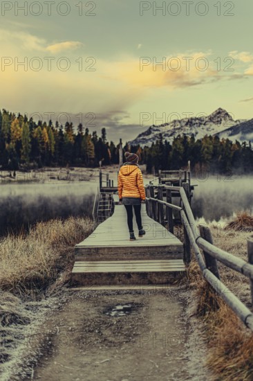 Young woman at Lake Staz near Sankt Moritz in the Engadine in Switzerland. Morning atmosphere with