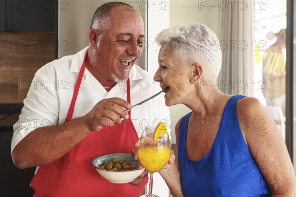 A joyful senior couple engages in a playful and affectionate interaction in a bright kitchen during
