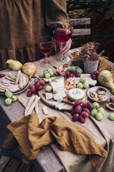 A rustic setup featuring a delicious cheese and fruit platter paired with two glasses of red wine.