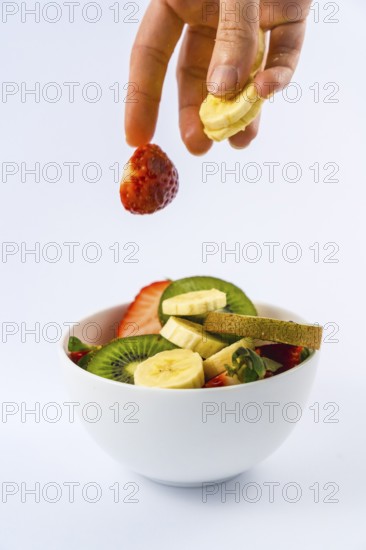 Introducing ingredients from above with a woman's hand, recipe for a fruit salad with kiwis,