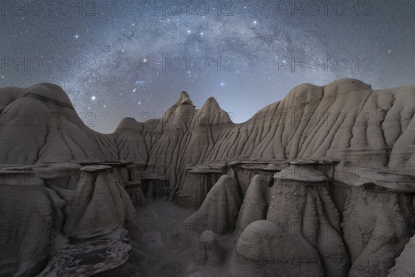 A serene night sky filled with stars illuminates the rugged, textured rock formations at a Utah,