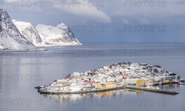Scenic winter view of Husoy, Norway, with snow-covered houses nestled between serene waters and