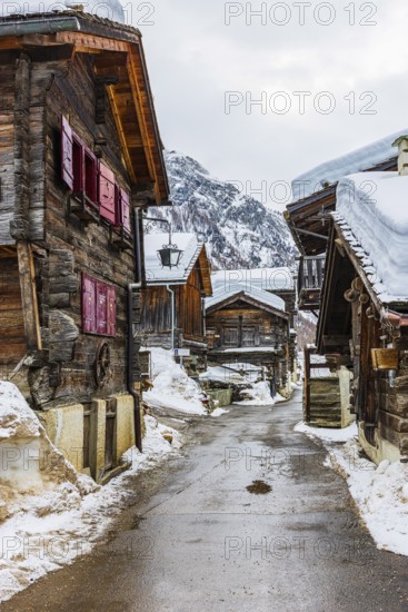 Street with historic old snow-covered wooden houses, mountain village of Zinal, Val d'Anniviers,