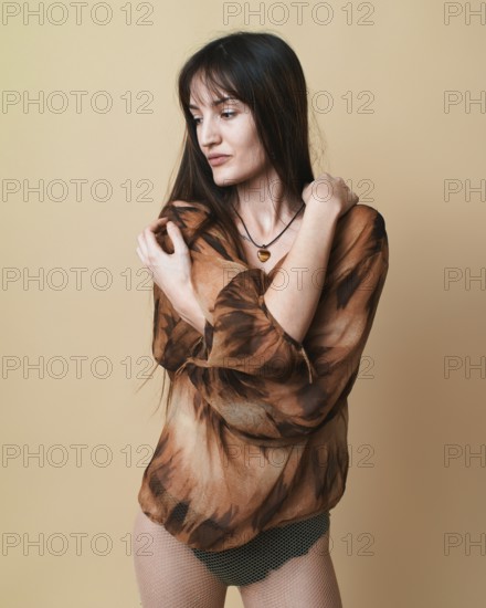 Studio portrait of a young woman posing with a thoughtful expression, wearing a patterned blouse