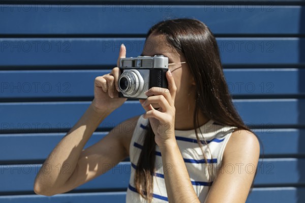 A young woman joyfully explores city life through the lens of a vintage camera, embodying the