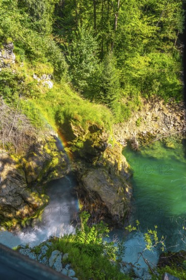 Stunning rainbow forming over waterfall cascading into turquoise water in vintgar gorge near bled,