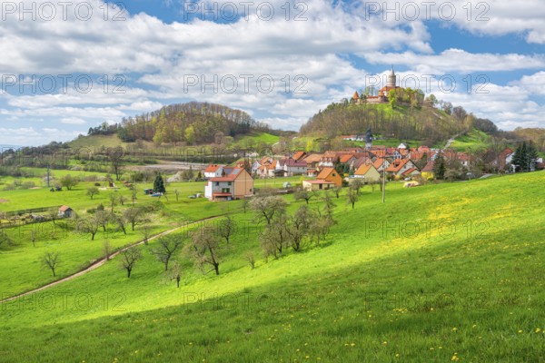View of hilly landscape with the village of Seitenroda and Leuchtenburg in spring, in front a green