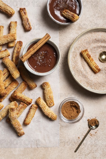 Top view of homemade churros generously dusted with sugar and cinnamon, accompanied by a rich