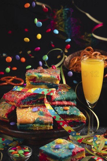 Colourful pieces of cake with sparkling wine and flying chocolate drops in a lively party
