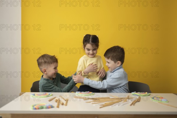 Three children engage in a playful educational lesson in a vibrant yellow classroom. Smiling faces
