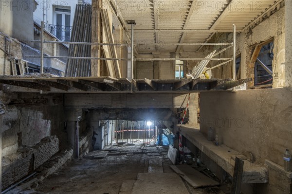 A construction site inside a partially renovated building features an exposed concrete structure,