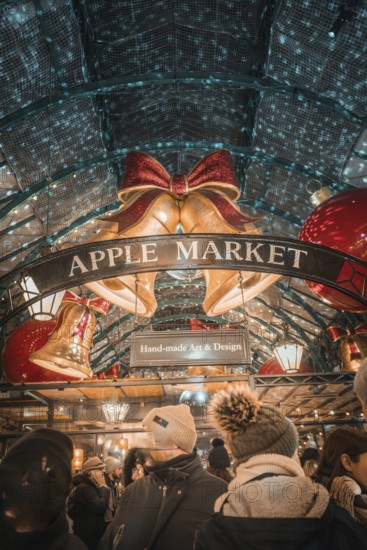 Visitors to Apple Market surrounded by Christmas bells and a sign with handmade art & design,