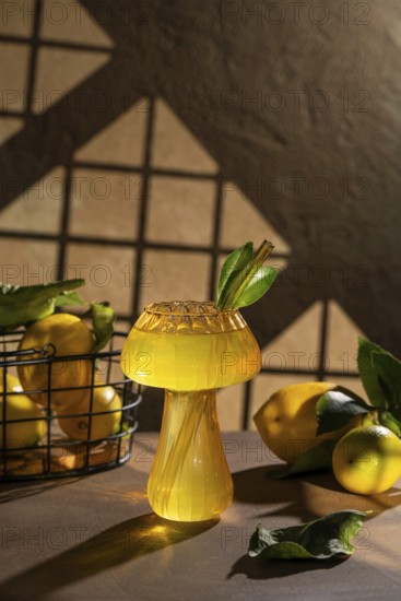 A refreshing lemon drink served in an artistic glass, adorned with green leaves and surrounded by