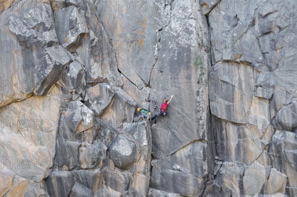 Climbers scale a rugged cliff using traditional techniques, highlighting skill, adventure, and a