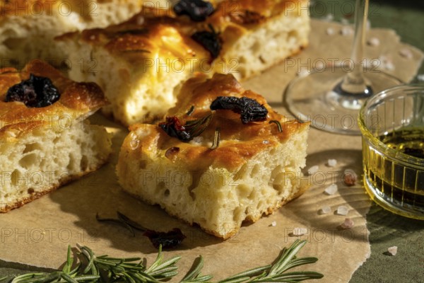 Golden homemade focaccia topped with sun dried tomato and rosemary. Served with olive oil, this