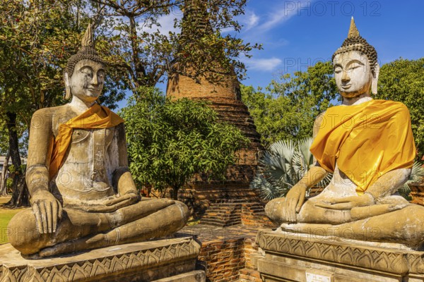 Stone Buddha statues decorated with yellow cloths, historic Buddhist temple complex, Ayutthaya,