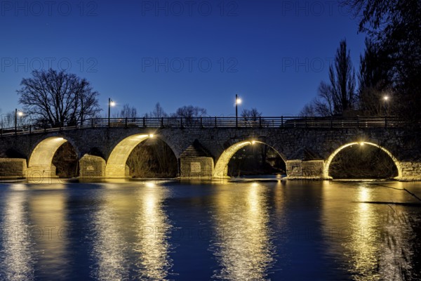 Night view of an illuminated bridge with lights reflecting in the quiet river, The Burgau Bridge in