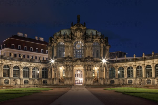 The Zwinger Palace in Dresden, Germany, is beautifully illuminated under a deep blue night sky.