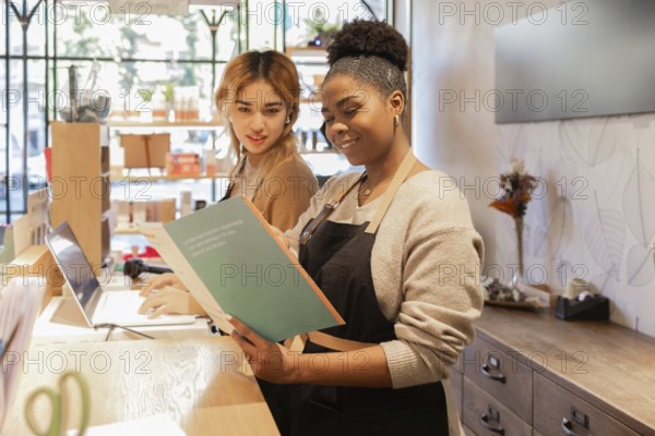 Two workers in a cosmetics store engage in tasks at the counter. One reads a catalog while the