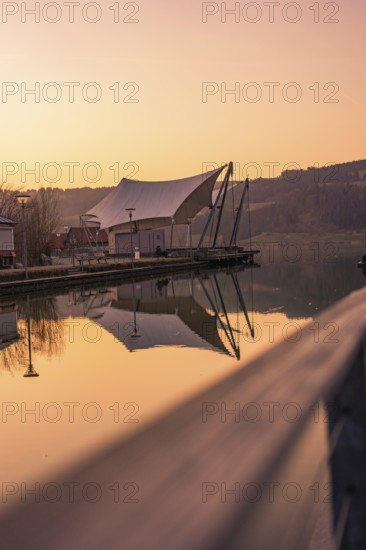 Large tent next to a pier by the lake, quiet atmosphere at dusk and reflection in the water, Großer