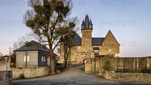 Evening view of a castle with courtyard, illuminated by warm light in front of sunset, Spangenberg