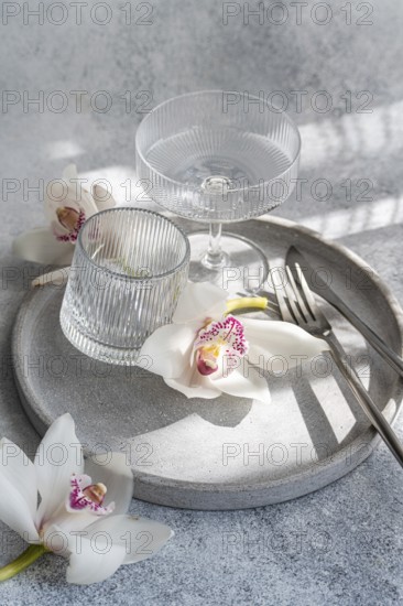 A refined dining setup featuring ribbed glassware, delicate orchids, and sleek cutlery on a