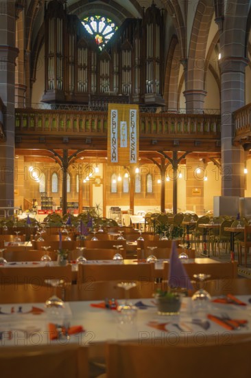 Interior view of a church with organ in the background and laid tables in the foreground,