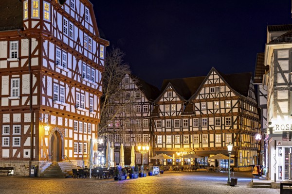 Night scene with illuminated half-timbered houses and a café in a rustic setting, The old town