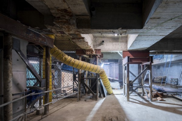 A construction site undergoing structural reinforcement features steel supports, exposed concrete