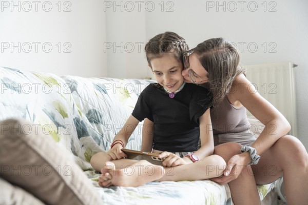 A family shares a tender moment with a disabled girl who has a tracheostomy using phone. The image