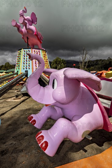 Pink elephant figures of a stopped carousel on a cloudy day, amusement park and carousel in Nuwara