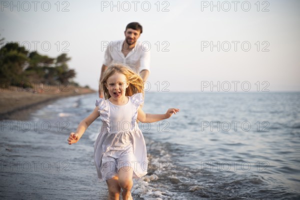 A young girl runs barefoot through the shallow waves of an Italian beach, smiling with joy as her