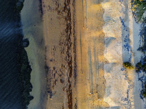 Aerial shot of a sandy beach during sunset, casting long shadows across the sand in the Great Ocean