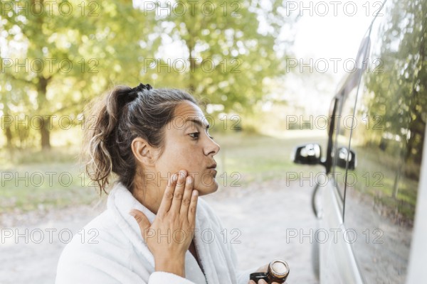 A woman enjoys her skincare routine while experiencing the freedom of van life in autumn. Captured