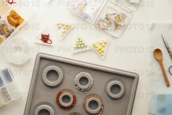 Top view of a creative jewelry making setup in a studio with tools like scissors, a wooden spoon,