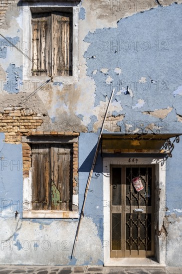 Dilapidated blue house facade with entrance door and windows, colourful houses on the island of