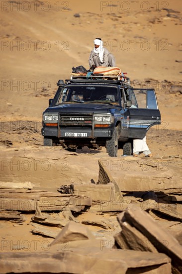 An off-road vehicle with people in traditional clothing stands in a vast desert landscape, Off-road