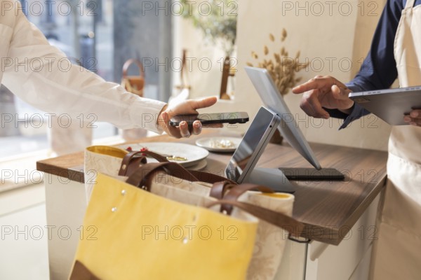 A customer makes a contactless payment with a smartphone in a bag store. The transaction occurs at