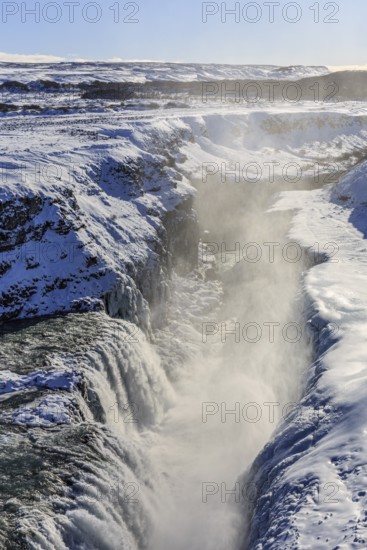 Large waterfall in a gorge in the snow, winter, sunny, backlight, spray, Gullfoss, Golden Circle,
