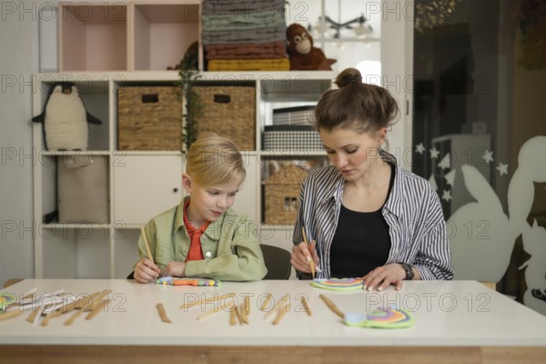 A teacher guides a child through a fun art lesson. The room is filled with colorful supplies,