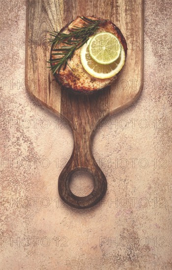 Salmon steak, fried, on a cutting board, top view, rosemary, lemon and lime, homemade, one serving,