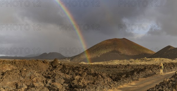 A vibrant rainbow arcs over the rugged volcanic terrain of Timanfaya National Park in Lanzarote,