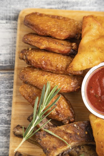 Set of snacks: nachos, chicken wings, fried ribs, bean tortillas on a cutting board on a gray
