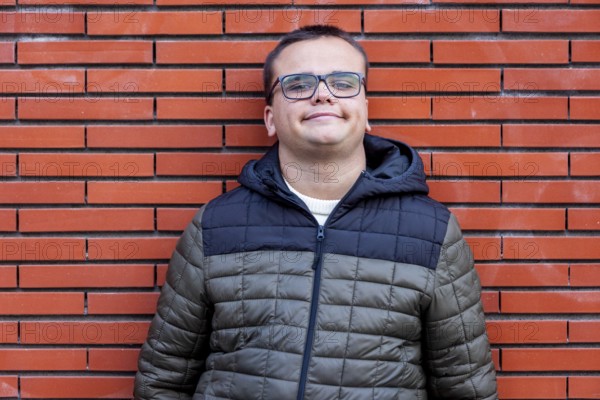 Man with an intellectual disability smiles warmly while leaning against a brick wall. His relaxed