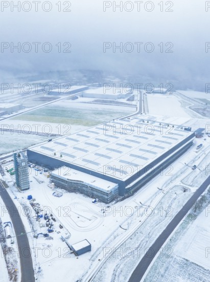 Large industrial plant in the snow, surrounded by roads, seen from the air, gives a sober winter