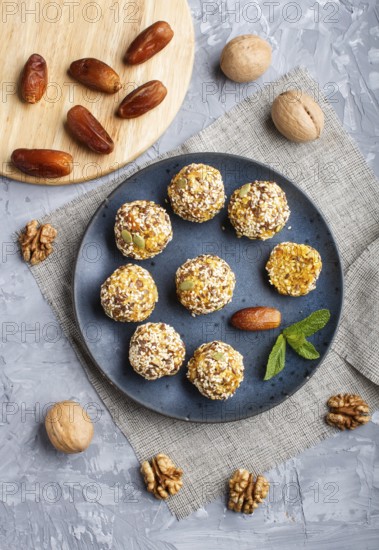 Energy ball cakes with dried apricots, sesame, linen, walnuts and dates with green mint leaves on a