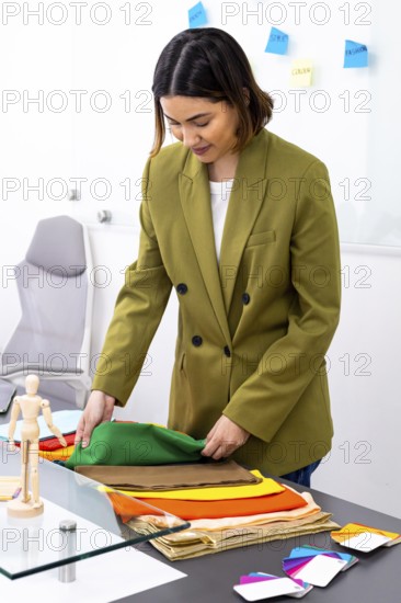 A professional image consultant in an office setting carefully selects vibrant fabrics for a