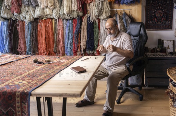 An Iranian master craftsman meticulously restores a carpet in his well-organized workshop in